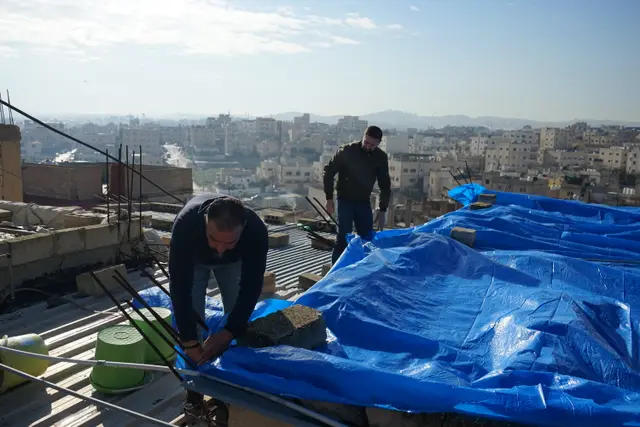 Volunteers repairing a refugee family's roof before winter